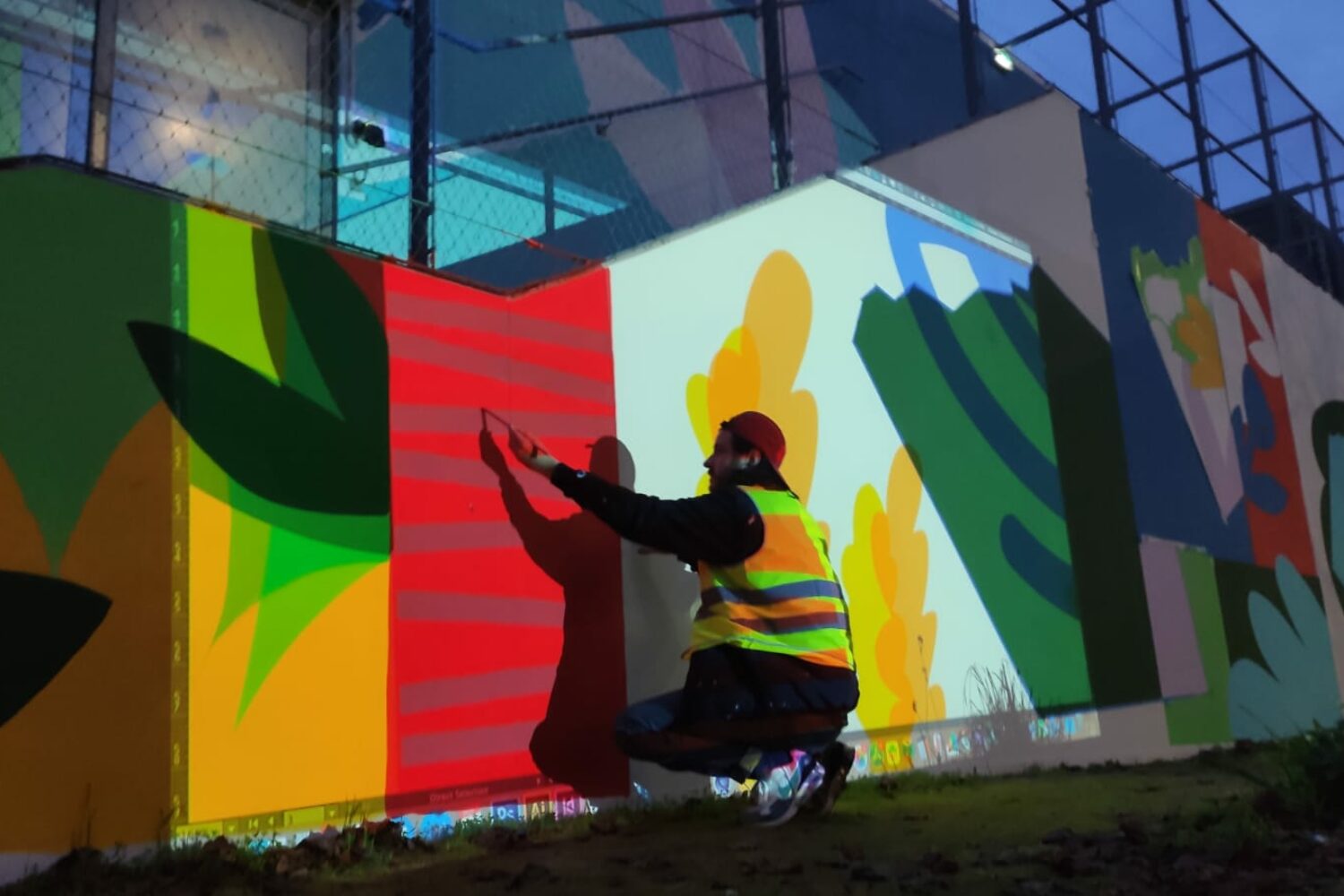 Olivier Charland en train de tracer et peindre les éléments de la murale