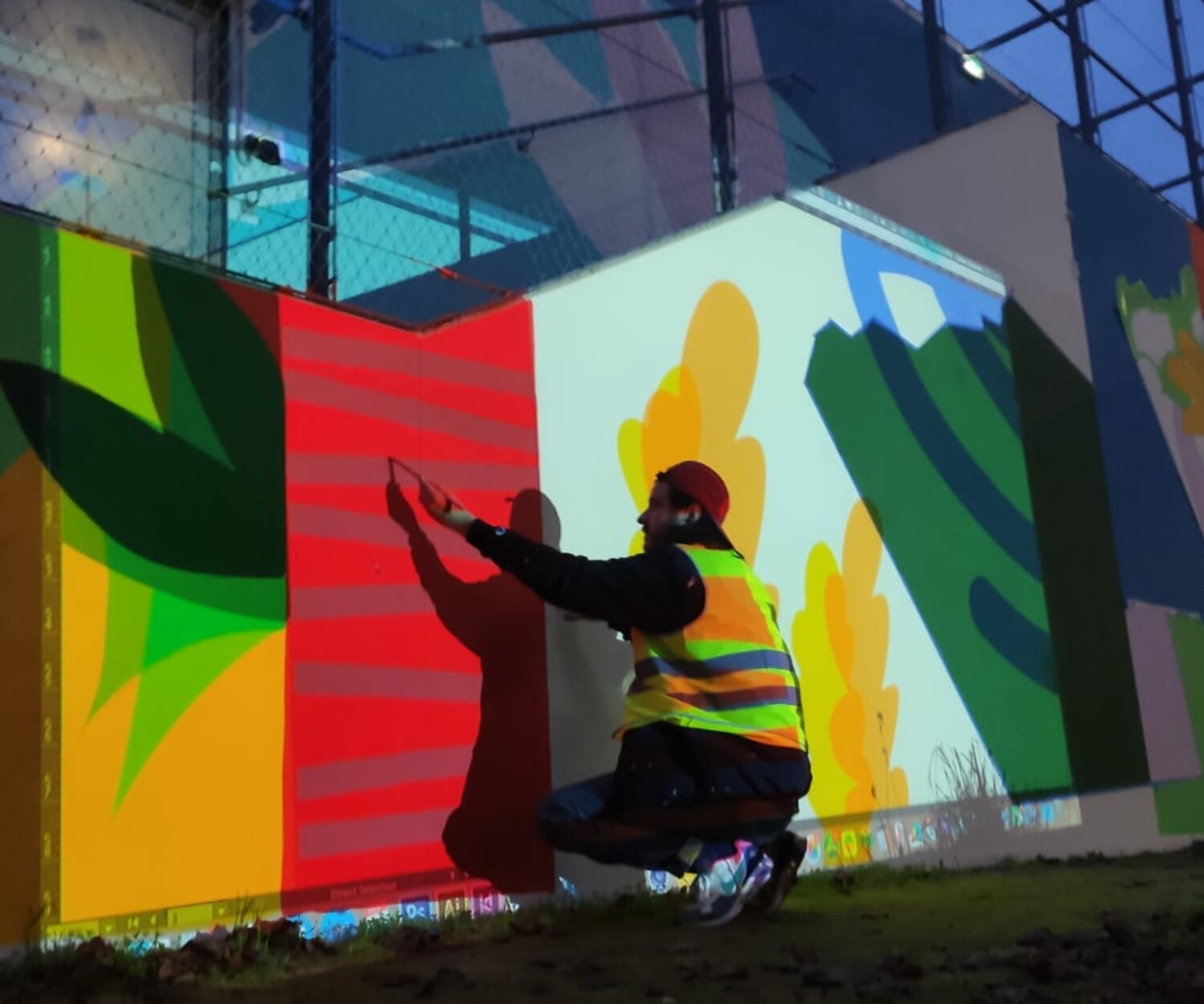 Olivier Charland en train de tracer et peindre les éléments de la murale